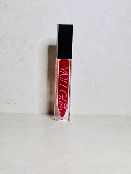 Red Velvet Lip Gloss by YNH Glow - Shimmering red lip gloss in a glossy tube, featuring a vibrant red shade with subtle sparkling flecks for a dazzling, high-shine finish.