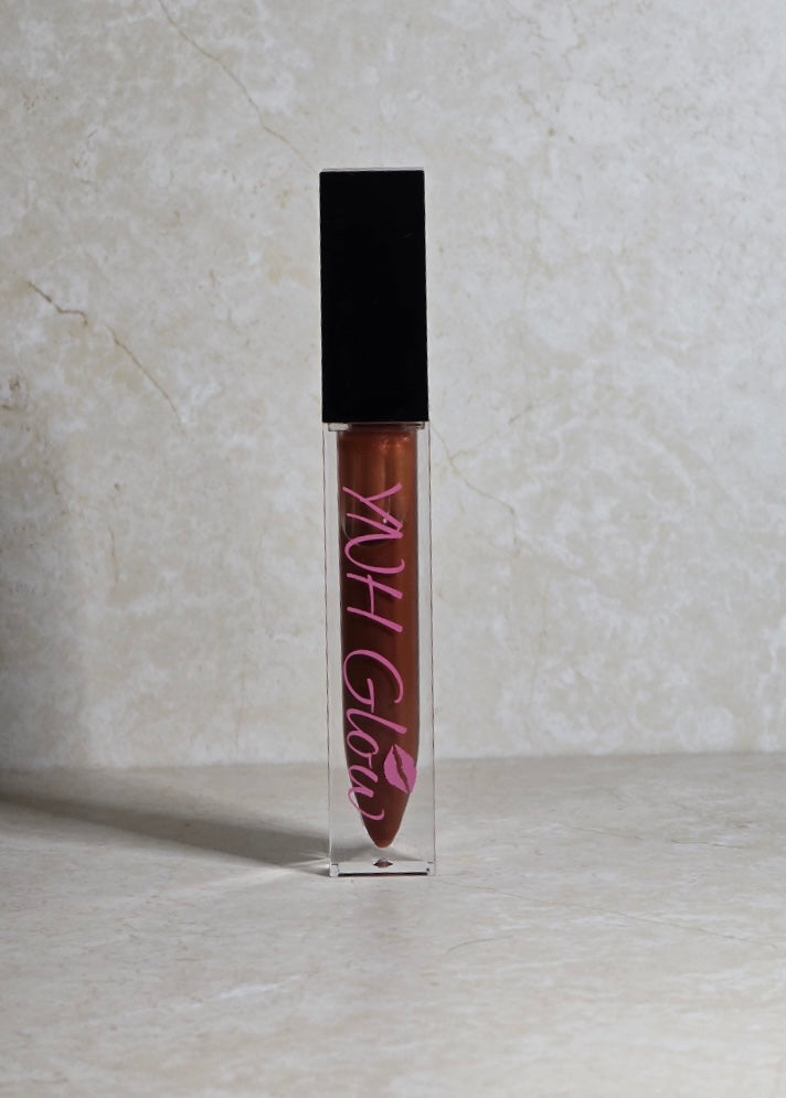 Coco Lip Gloss by YNH Glow, in a sleek tube, with a smooth, glossy texture and a rich, warm shade.