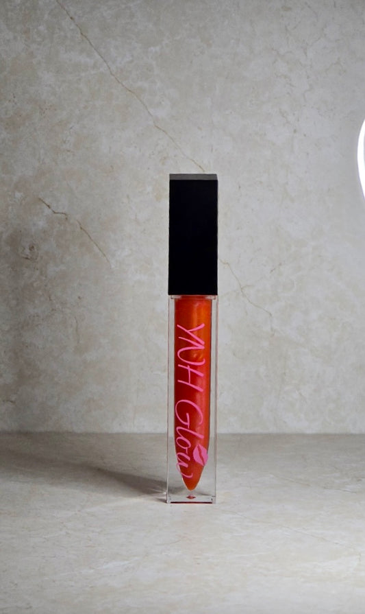 Miami Lip Gloss by YNH Glow:
Coral-orange lip gloss in a glossy tube, featuring a vibrant, bold hue with a smooth, shiny finish.